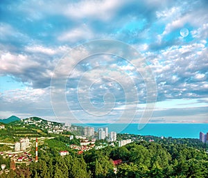 Aerial view of blue coast of Black Sea near  Sochi city with residential houses and recreation area under summer cloudy sky