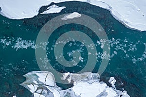 Aerial of a blue and green river with snow and crushed ice during an ice drift in winter in the Altai mountains in Russia