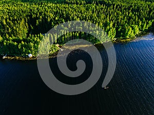 Aerial view of blue lake with a fishing boat and green woods on a sunny summer day in Finland