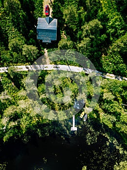 Aerial view of blue lake with green forests in Finland. Wooden house, sauna, boats and fishing pier by the lake