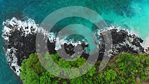 Aerial view of blue ocean and black rocks in tropical island.