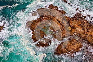 Aerial view of blue ocean surrounding  etched rocks and boulders