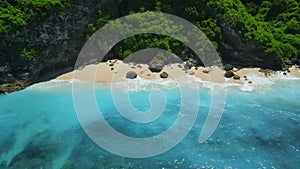 Aerial view of blue ocean with tropical beach under rocks in Bali