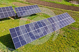 Aerial view of blue photovoltaic solar panels mounted on backyard ground for producing clean ecological electricity