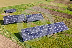 Aerial view of blue photovoltaic solar panels mounted on backyard ground for producing clean ecological electricity