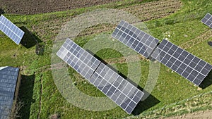 Aerial view of blue photovoltaic solar panels mounted on backyard ground for producing clean ecological electricity