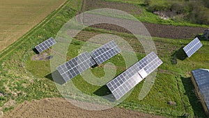 Aerial view of blue photovoltaic solar panels mounted on backyard ground for producing clean ecological electricity