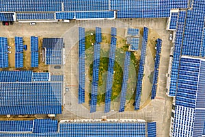 Aerial view of blue photovoltaic solar panels mounted on industrial building roof for producing clean ecological