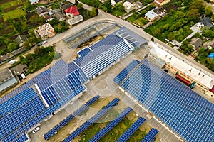 Aerial view of blue photovoltaic solar panels mounted on industrial building roof for producing clean ecological