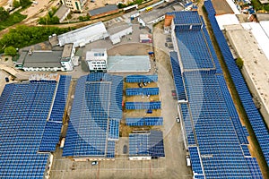 Aerial view of blue photovoltaic solar panels mounted on industrial building roof for producing clean ecological