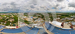 Aerial view of blue photovoltaic solar panels mounted on industrial building roof for producing clean ecological electricity.