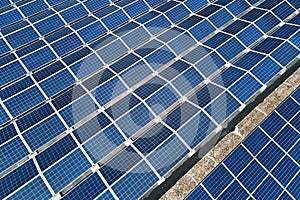 Aerial view of blue photovoltaic solar panels mounted on industrial building roof for producing green ecological