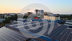 Aerial view of blue photovoltaic solar panels mounted on industrial building roof for producing green ecological