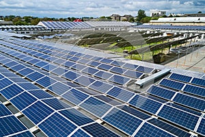 Aerial view of blue photovoltaic solar panels mounted on industrial building roof for producing green ecological