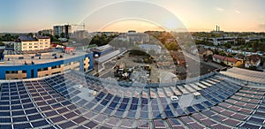 Aerial view of blue photovoltaic solar panels mounted on industrial building roof for producing green ecological