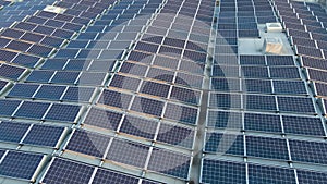 Aerial view of blue photovoltaic solar panels mounted on industrial building roof for producing green ecological