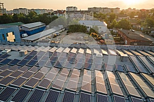 Aerial view of blue photovoltaic solar panels mounted on industrial building roof for producing green ecological