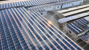 Aerial view of blue photovoltaic solar panels mounted on industrial building roof for producing green ecological