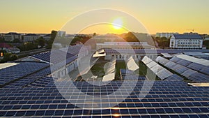 Aerial view of blue photovoltaic solar panels mounted on industrial building roof for producing green ecological