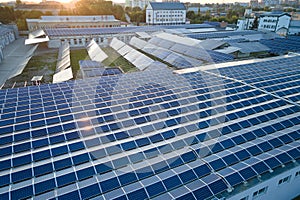 Aerial view of blue photovoltaic solar panels mounted on industrial building roof for producing green ecological