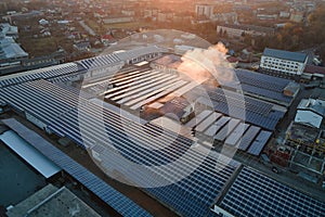 Aerial view of blue photovoltaic solar panels mounted on industrial building roof for producing green ecological