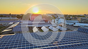 Aerial view of blue photovoltaic solar panels mounted on industrial building roof for producing green ecological