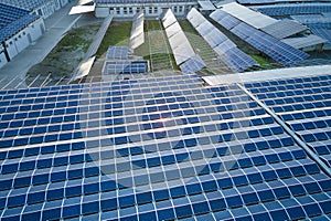 Aerial view of blue photovoltaic solar panels mounted on industrial building roof for producing green ecological