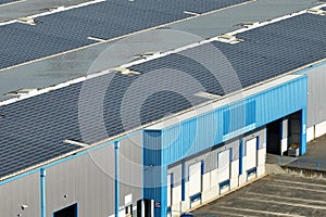 Aerial view of blue photovoltaic solar panels mounted on industrial building roof for producing green ecological