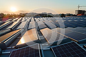 Aerial view of blue photovoltaic solar panels mounted on industrial building roof for producing green ecological