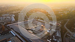 Aerial view of blue photovoltaic solar panels mounted on industrial building roof for producing green ecological