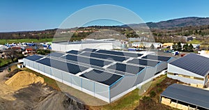 Aerial view of blue photovoltaic solar panels mounted on industrial building roof for producing green ecological