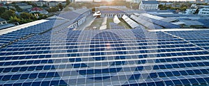 Aerial view of blue photovoltaic solar panels mounted on industrial building roof for producing green ecological