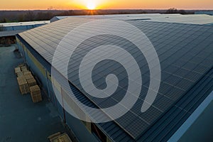 Aerial view of blue photovoltaic solar panels mounted on industrial building roof for producing green ecological