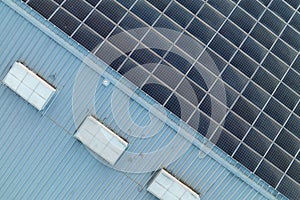 Aerial view of blue photovoltaic solar panels mounted on industrial building roof for producing green ecological