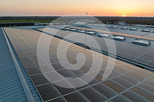 Aerial view of blue photovoltaic solar panels mounted on industrial building roof for producing green ecological