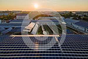 Aerial view of blue photovoltaic solar panels mounted on industrial building roof for producing green ecological