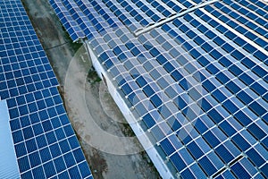 Aerial view of blue photovoltaic solar panels mounted on industrial building roof for producing green ecological