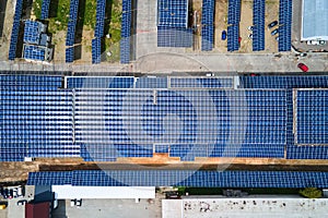 Aerial view of blue photovoltaic solar panels mounted on industrial building roof for producing green ecological