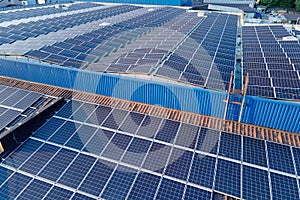 Aerial view of blue photovoltaic solar panels mounted on industrial building roof for producing green ecological