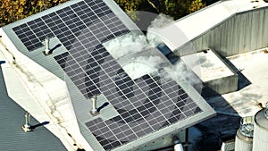 Aerial view of blue photovoltaic solar panels mounted on industrial building roof for producing green ecological