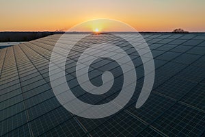 Aerial view of blue photovoltaic solar panels mounted on industrial building roof for producing green ecological