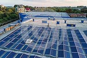 Aerial view of blue photovoltaic solar panels mounted on industrial building roof for producing green ecological