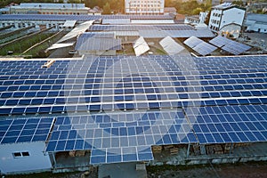 Aerial view of blue photovoltaic solar panels mounted on industrial building roof for producing green ecological