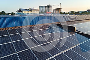 Aerial view of blue photovoltaic solar panels mounted on industrial building roof for producing green ecological