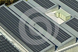 Aerial view of blue photovoltaic solar panels mounted on industrial building roof for producing green ecological