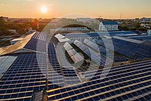 Aerial view of blue photovoltaic solar panels mounted on industrial building roof for producing green ecological