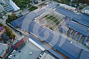 Aerial view of blue photovoltaic solar panels mounted on industrial building roof for producing green ecological