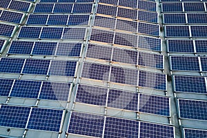 Aerial view of blue photovoltaic solar panels mounted on industrial building roof for producing green ecological