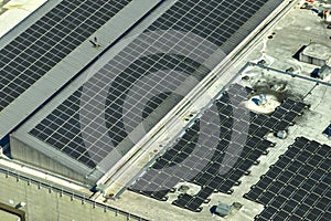 Aerial view of blue photovoltaic solar panels mounted on industrial building roof for producing green ecological