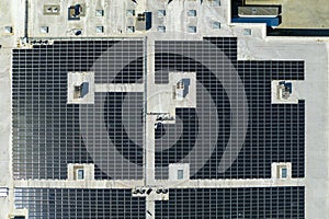 Aerial view of blue photovoltaic solar panels mounted on industrial building roof for producing green ecological